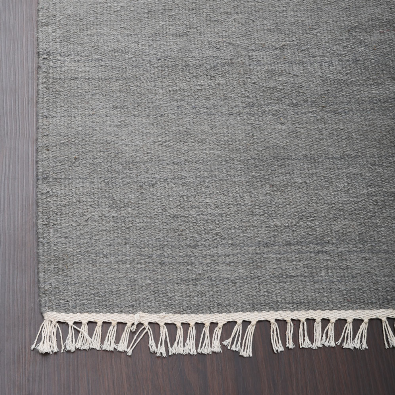Solid gray flatweave wool area rug with short cream fringe border.