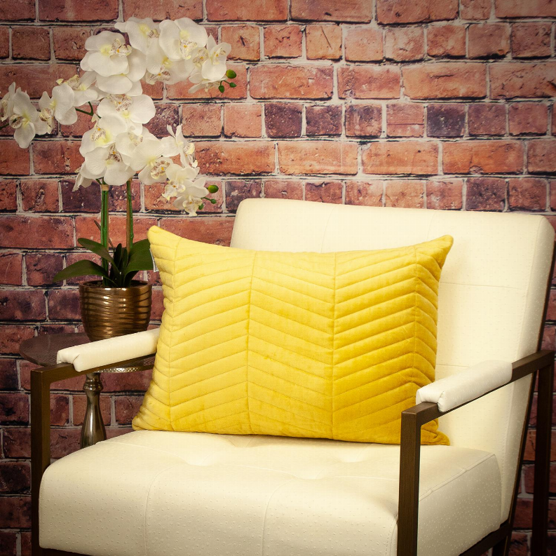 Yellow channel-quilted lumbar throw pillow on a light upholstered chair