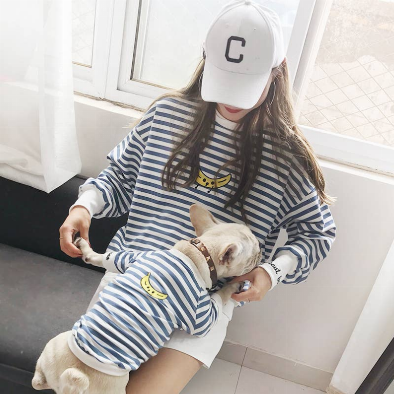 Striped pet and owner clothing set: owner in blue-and-white striped outfit holding a matching pet