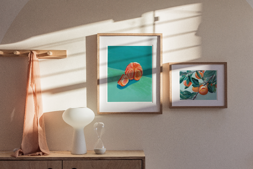 Framed botanical wall art print with orange blossoms and green leaves on teal