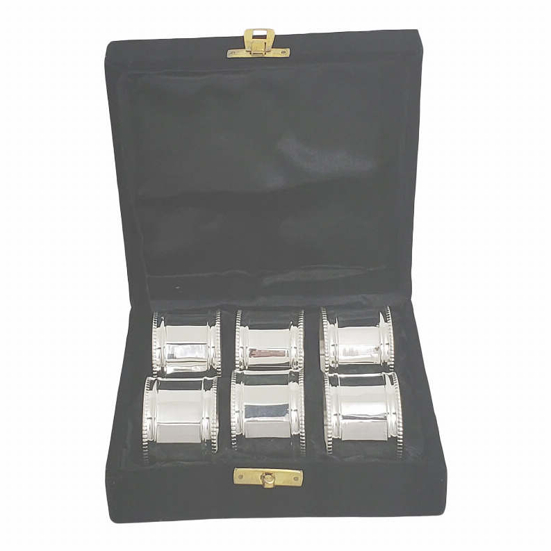 Six silver napkin rings with panel-and-bead details, shown in black case