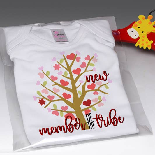 White baby onesie with colorful heart tree graphic and red script text on chest