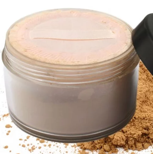 Mineral powder container with pale lid; loose powder scattered around the base
