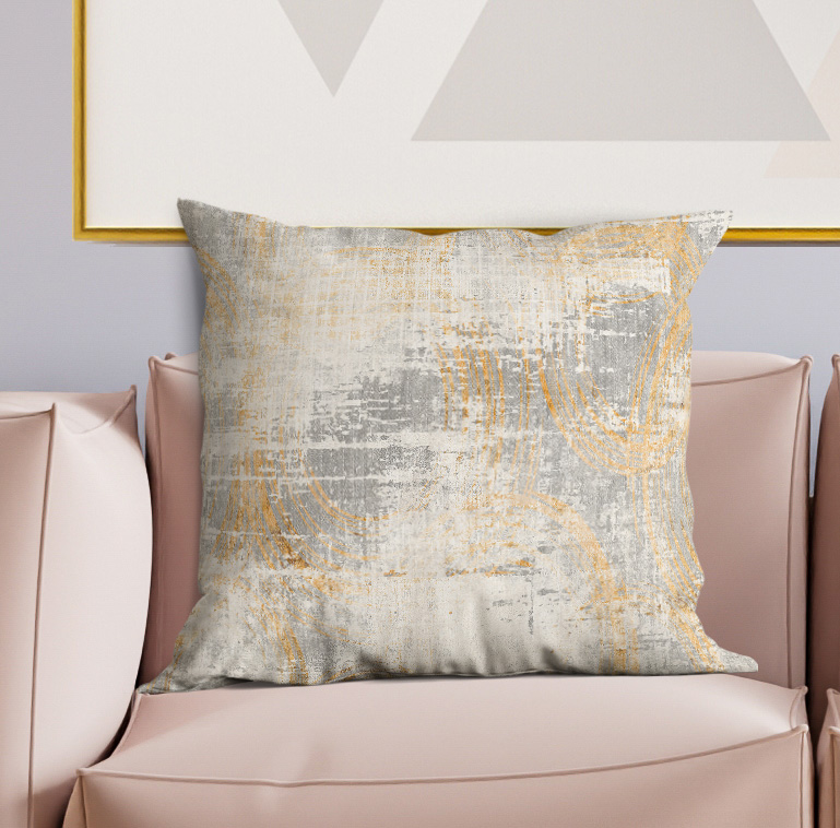 Square decorative pillow with light gray and gold abstract pattern, textured fabric