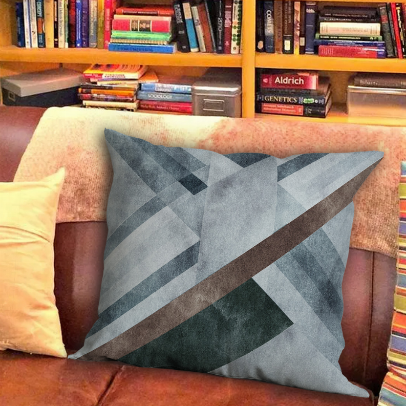 Decorative pillow with blue-gray geometric triangles and brown diagonal stripe.