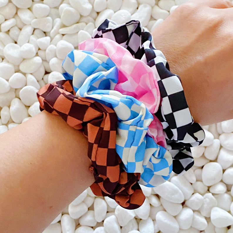 Multicolor checkerboard hair scrunchie with black, blue, pink, and brown squares.