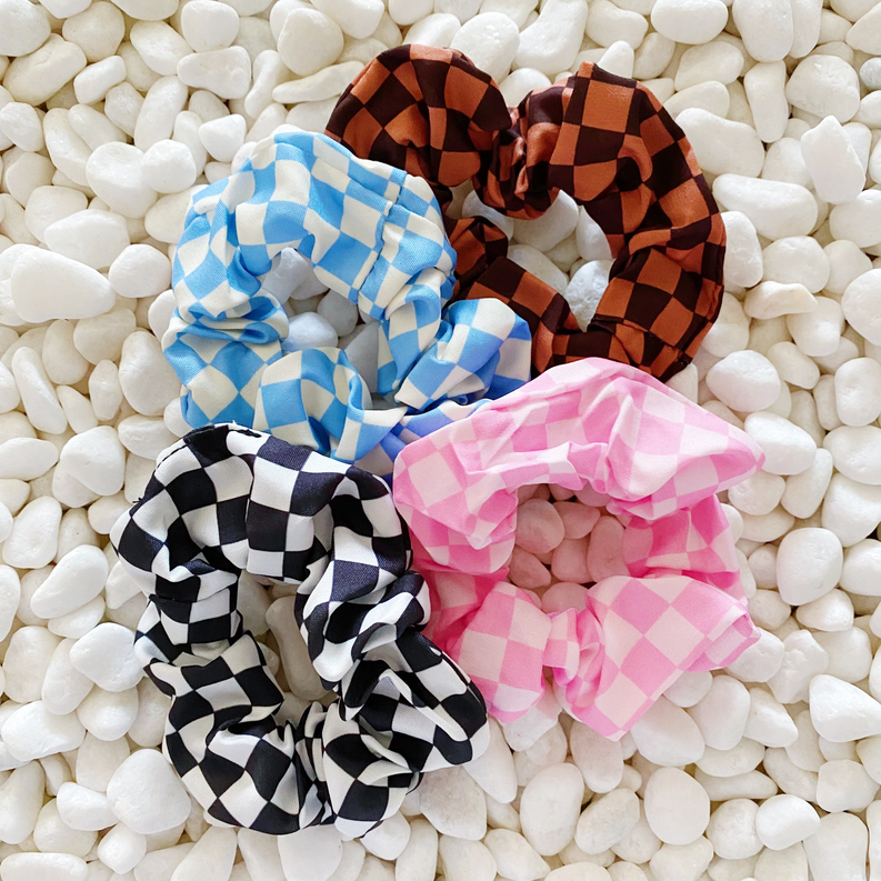 Four checkerboard hair scrunchies: orange-brown, blue, black/white, and pink check.