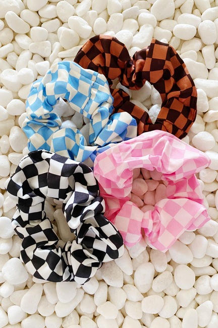 Four checkerboard hair scrunchies with orange-brown, blue, black/white, and pink plaid.