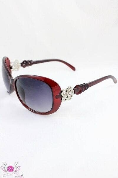 Red-brown sunglasses with purple-tinted lenses, braided temples, and white floral front detail