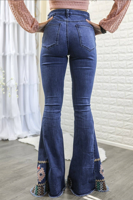 Dark blue high-rise bootcut jeans with embroidered patterned cuffs at bell hems.