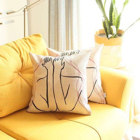 Printed throw pillow cover on a yellow sofa, white with black and red line-art faces
