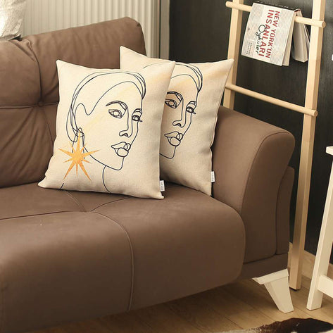 Two white printed throw pillow covers with line-art faces and gold starburst accents
