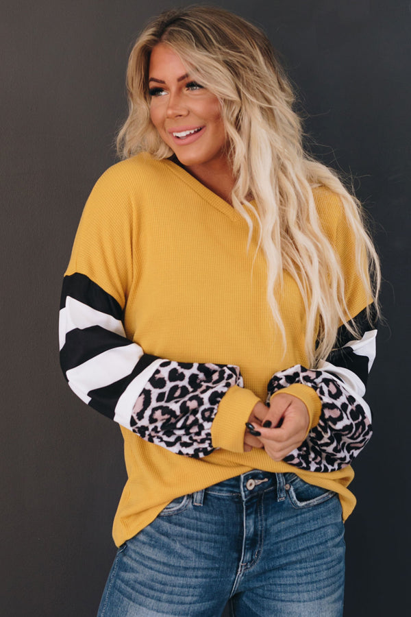 Mustard yellow long-sleeve top with leopard-print and black-and-white striped cuffs