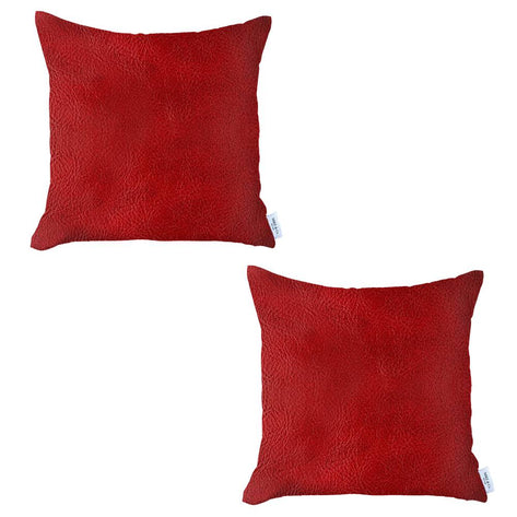 Two red square faux leather throw pillows with white tag on plain background