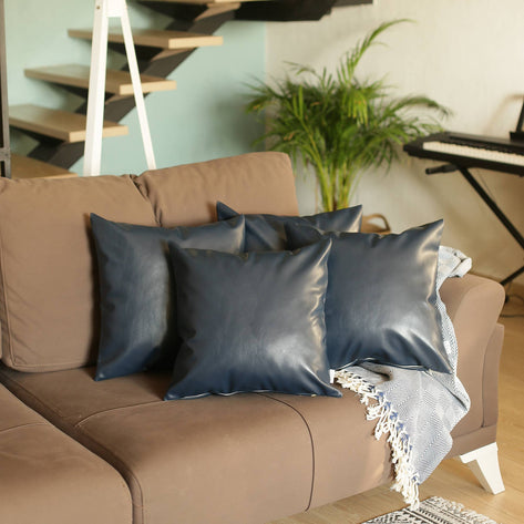 Navy faux leather square throw pillows on sofa, smooth sheen finish