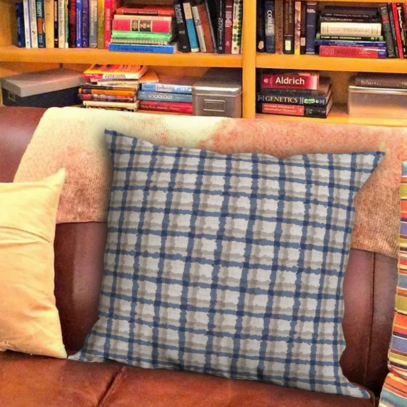 Square throw pillow with blue grid plaid pattern on beige background