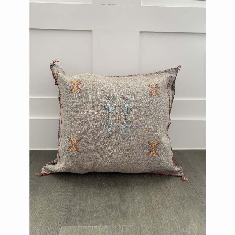 Gray decorative pillow cover with symmetrical blue-and-orange X patterns and tasseled trim