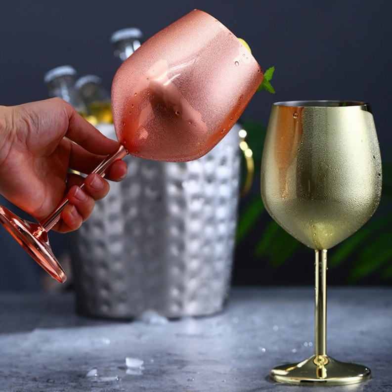 Rose-gold cocktail glass with lemon wedge, held in hand; mirrored metal finish
