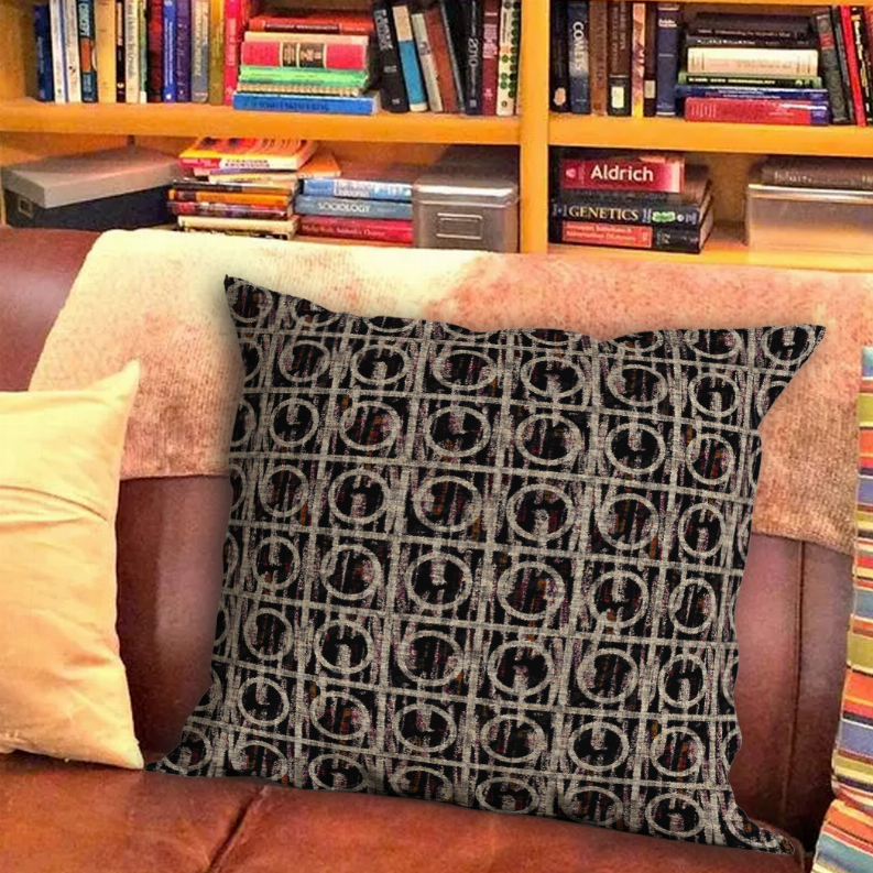 Square throw pillow with black and beige repeating logo pattern on textured cover