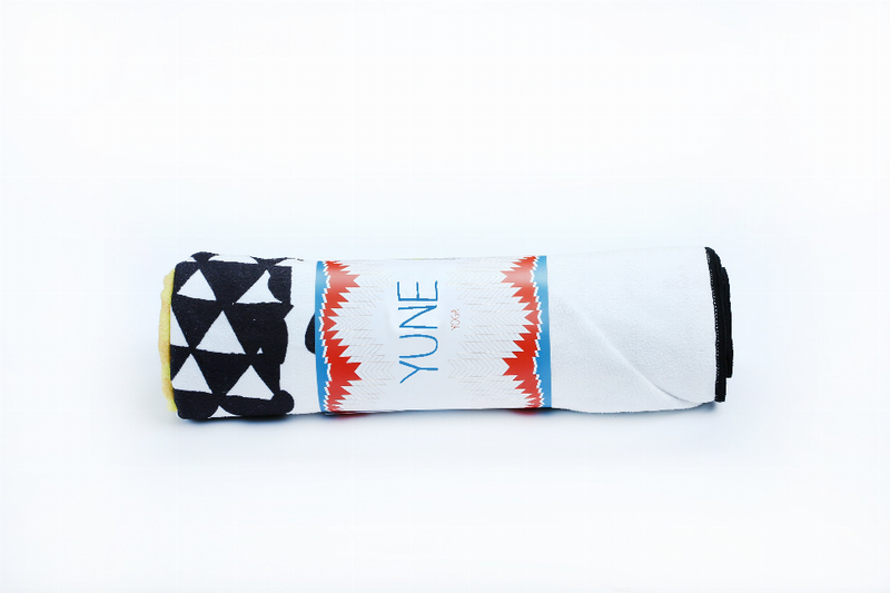 Rolled yoga towel with black triangle pattern and red burst stripe over white fabric