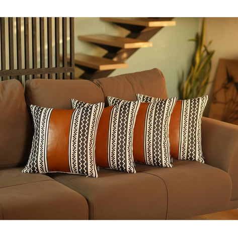 Stacked black-and-white striped accent pillows with solid tan backing on sofa