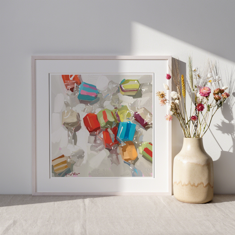Framed abstract wall art with multicolor geometric shapes next to cream flower vase