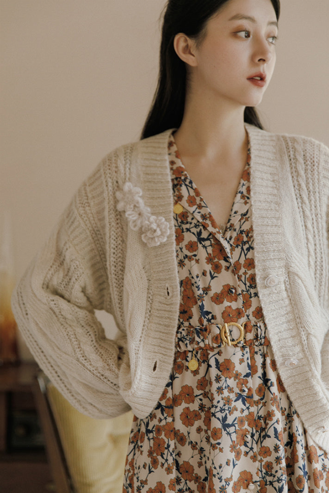 Cream crochet knit cardigan with textured sleeves and front button closure detail.