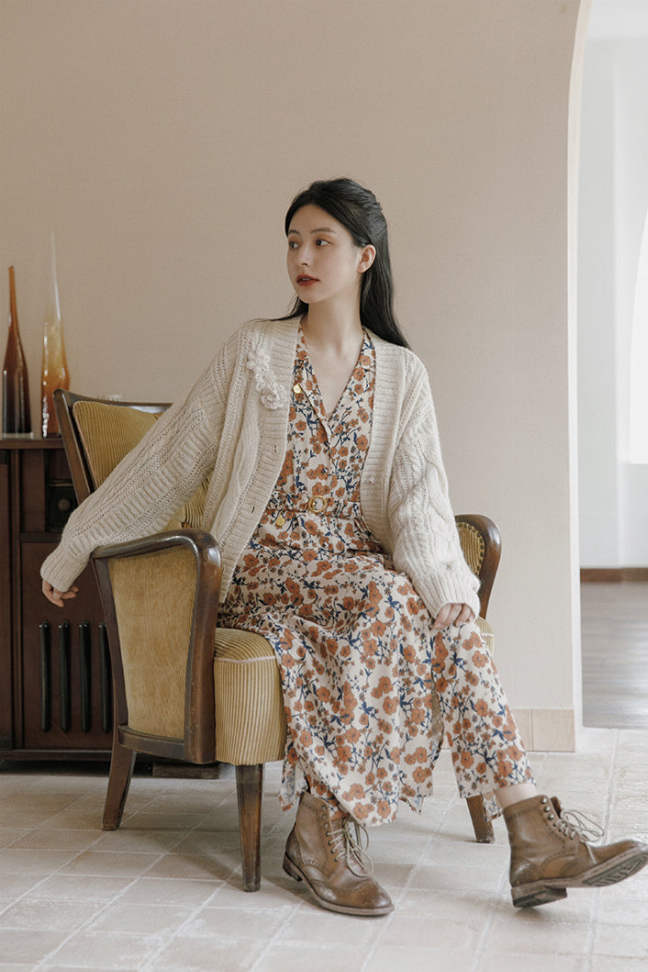 Cream crocheted cardigan sweater with floral applique and long sleeves, worn open.