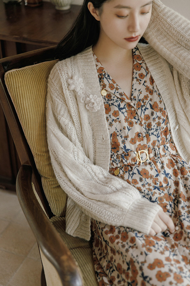 Cream knit cardigan detail with floral patch at chest and button front closure.