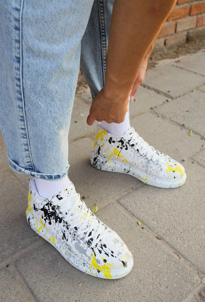 White high-top sneakers with yellow and black splatter print, lace-up with ribbed socks