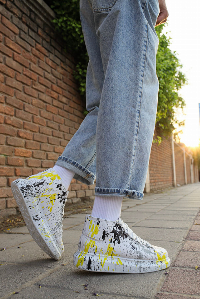White high-top sneakers with yellow/black splatter print and cuffed light-wash jeans