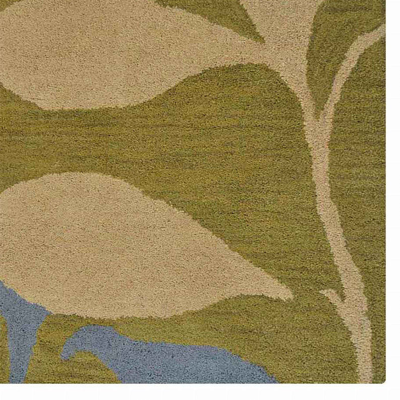Hand-tufted wool area rug close-up, tan and olive floral shapes with blue accents