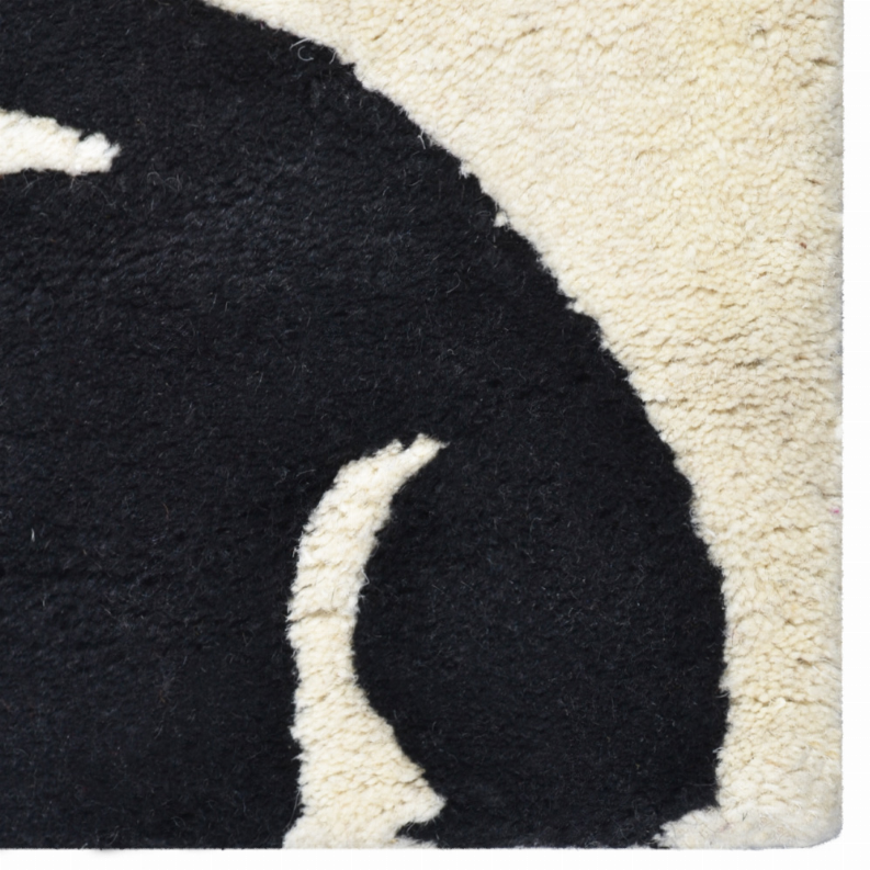 Close-up of black and ivory floral rug with textured cut-pile and curved motif