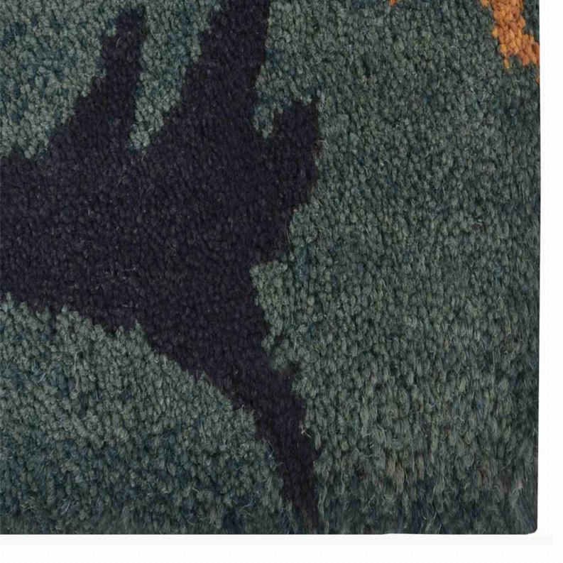 Hand-tufted wool area rug pile texture close-up, teal-gray with dark navy floral sections