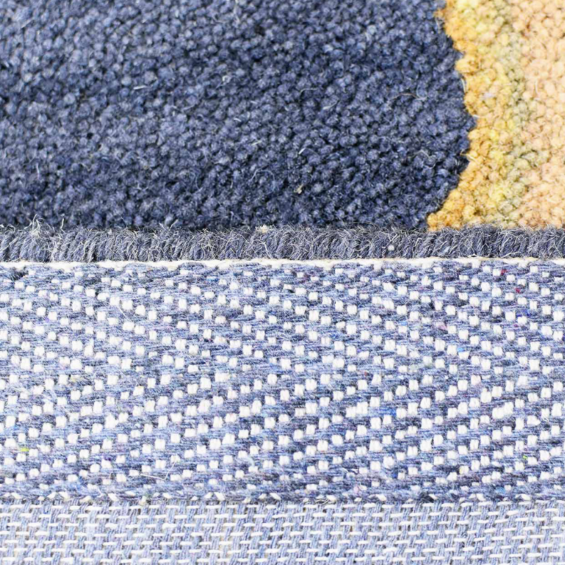 Hand-tufted wool rug edge with blue and cream binding and textured backing