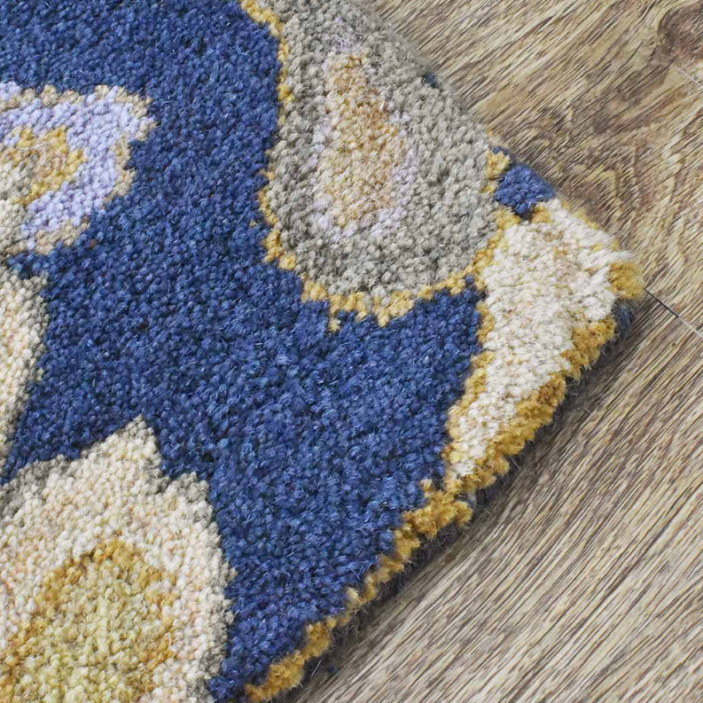 Hand-tufted wool rug corner detail in deep blue, cream, and yellow with textured pile.