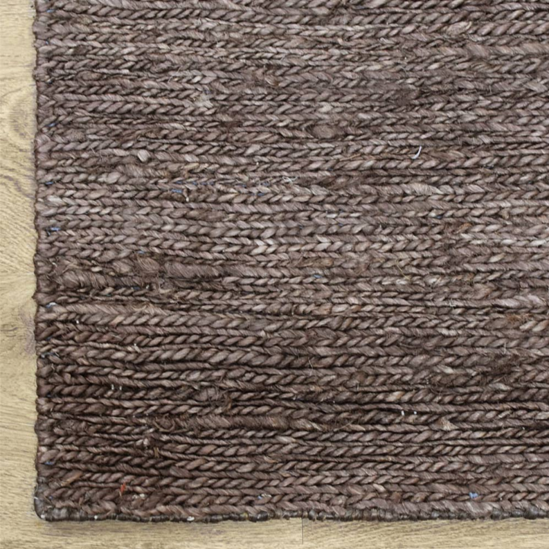 Brown jute area rug close-up, woven surface with speckled fibers