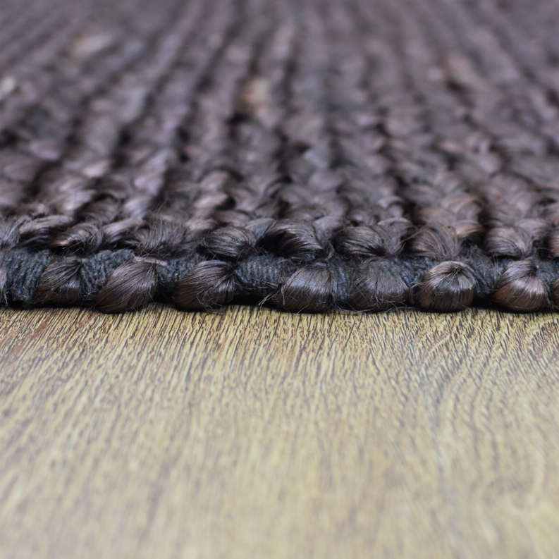 Jute area rug close-up of thick braided fibers in dark gray with subtle pinky undertones