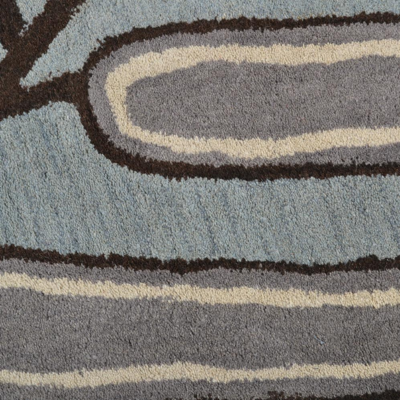 Hand-tufted wool area rug close-up, blue-gray with beige banding and dark brown border
