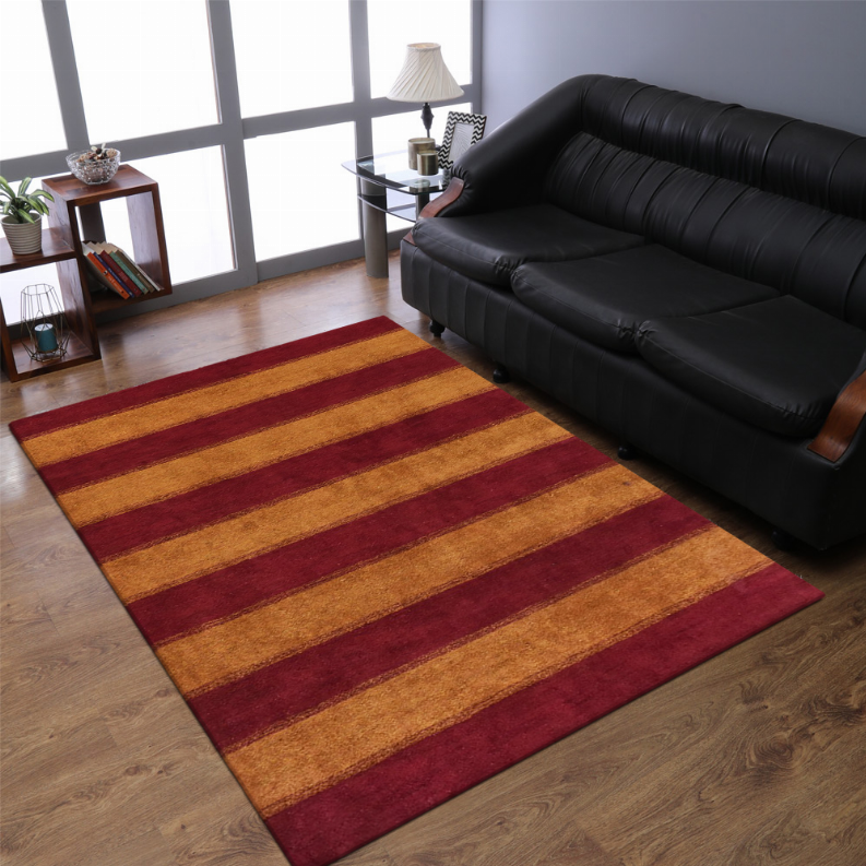 Striped area rug with burgundy and tan horizontal bands on a wood floor in front of a black sofa.