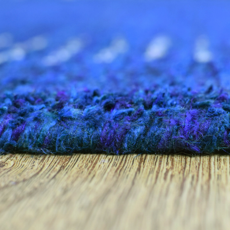 Blue rug with thick textured pile, close view of the rug edge and border.