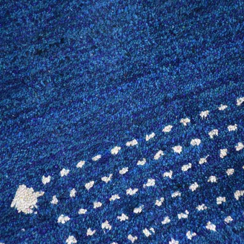 Blue rug pile texture with cream geometric cluster accents along a curved diagonal band.