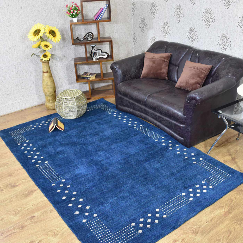 Blue area rug with white geometric border pattern and short textured pile.
