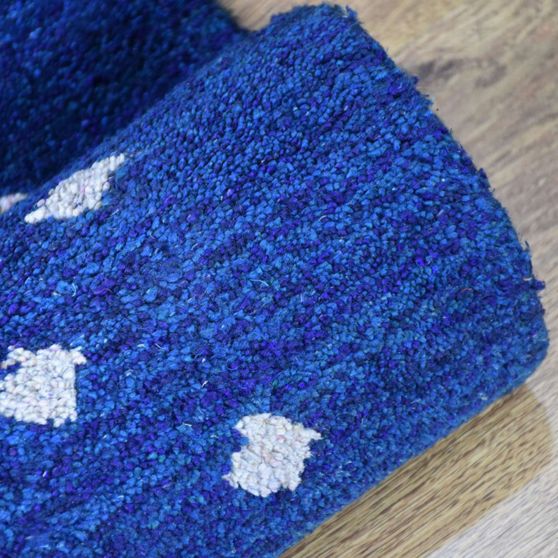 Deep blue rug corner with textured pile and small white diamond patches