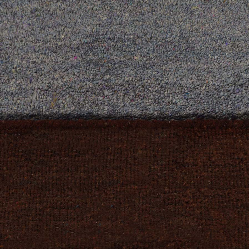 Close-up of dark brown rug texture with darker speckling and hints of red along the edge
