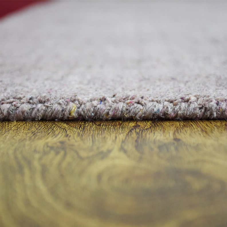 Area rug edge close-up with thick plush pile and yellowish underlayer