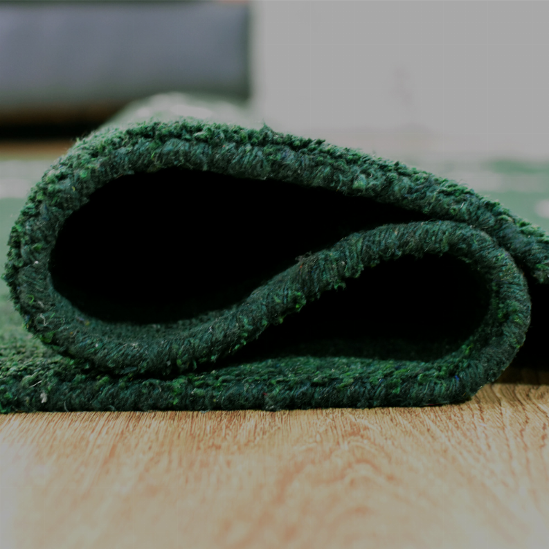 Rolled green area rug showing thick textured pile and dark underside