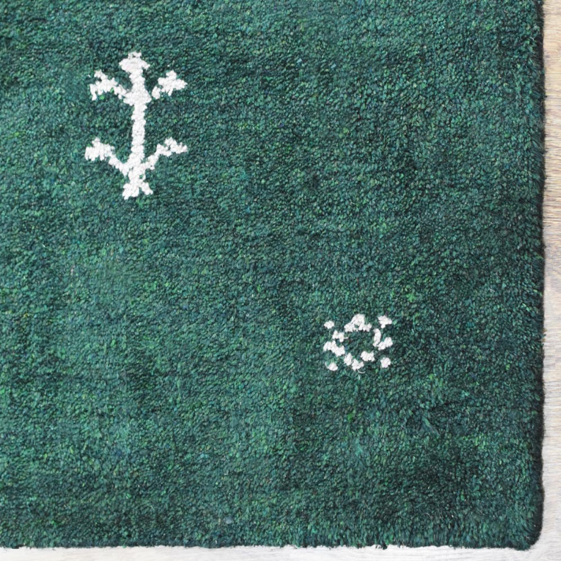 Green area rug corner with white motif clusters and textured short pile edge