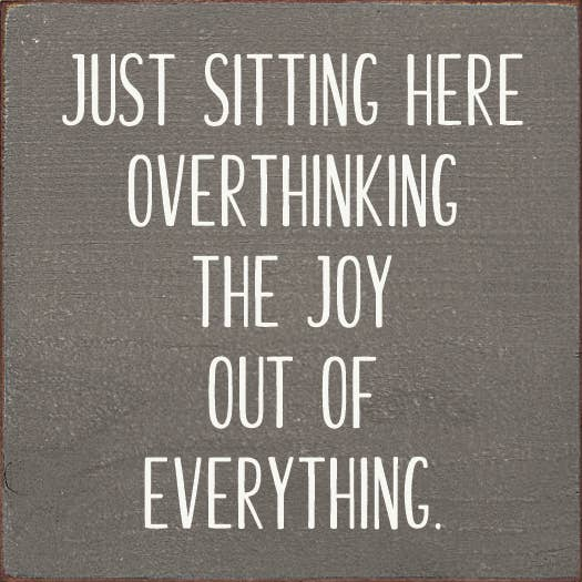 Inspirational wall sign with white quote text: JUST SITTING HERE OVERTHINKING