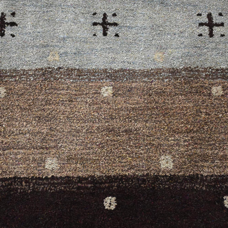 Macro view of area rug surface with speckled brown and gray fields and dark border